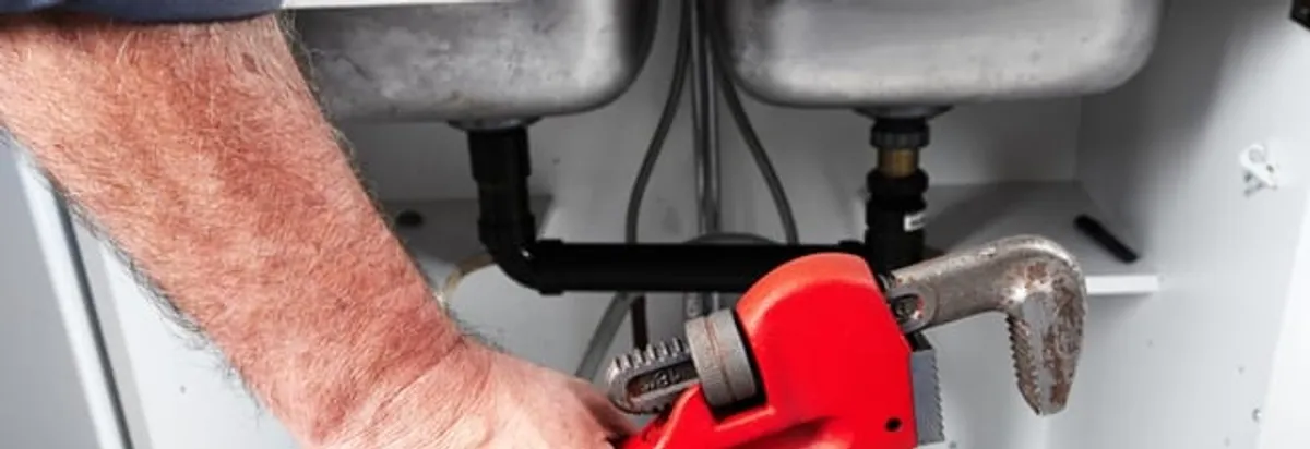 Garbage disposal repair technician tightening drain connections under a kitchen sink in Miami, FL
