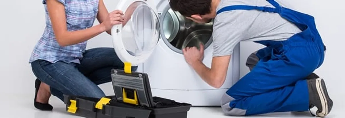Washer repair technician inspecting a front-load washing machine with tools in Miami, FL