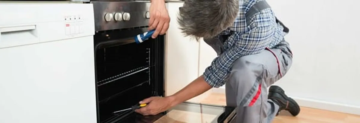 Oven repair technician inspecting and servicing an electric oven in Miami, FL