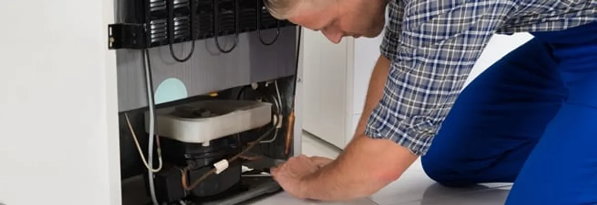 Refrigerator repair technician servicing the compressor and condenser area in Miami, FL