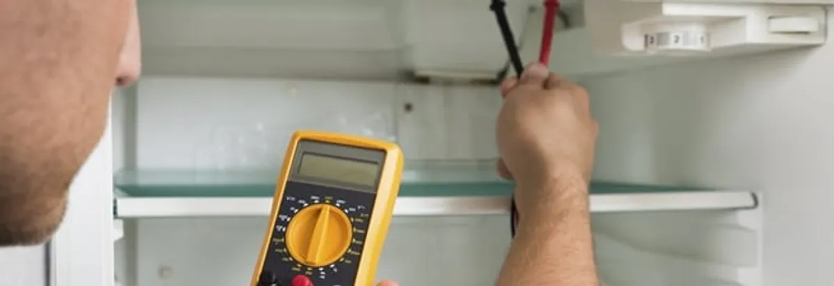 Refrigerator repair technician testing electrical components with a multimeter in Miami, FL