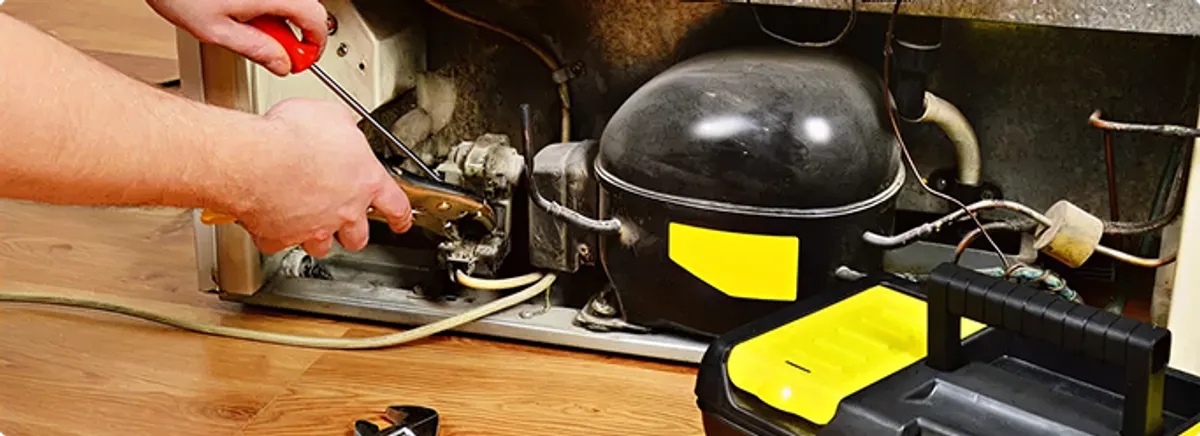 Refrigerator repair technician fixing the compressor and wiring in Miami, FL
