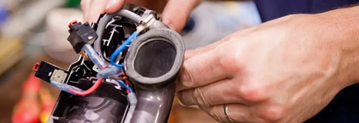 Vacuum repair technician reconnecting wiring and components in Miami, FL